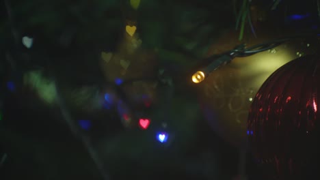 close up of a christmas tree lit up with tinsel and christmas ornaments