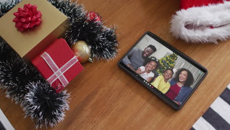 sonriente familia afroamericana saludando en la videollamada de navidad en la tableta