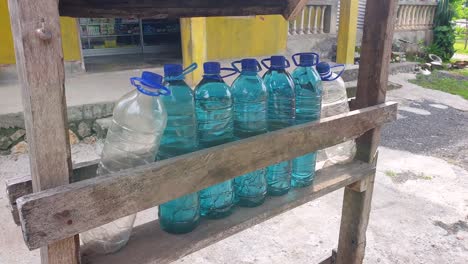 fila de botellas de agua de plástico llenas de gasolina azul en un puesto al borde de la carretera en la frontera de timor leste e indonesia, sudeste de asia