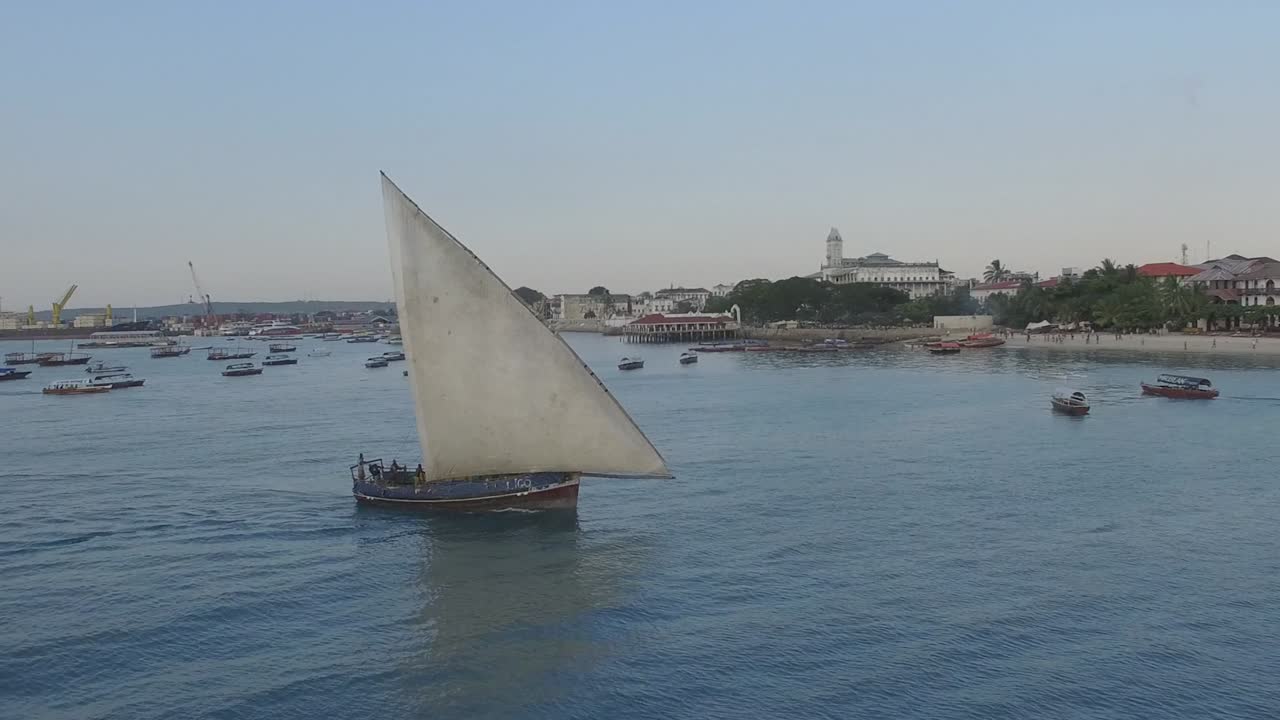 Aerial shot of a boat sailing next to the shores of Stone Town in Zanzibar, Tanzania
