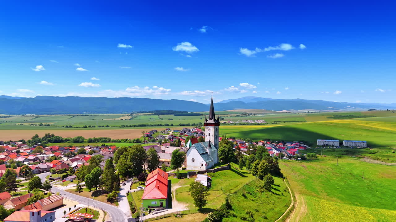 Lovely rural area with an old church in the middle. Countryside in Slovakia. Mountain range at backdrop. Aerial view