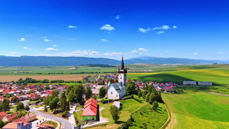 lovely rural area with an old church in the middle. countryside in slovakia. mountain range at backdrop. aerial view