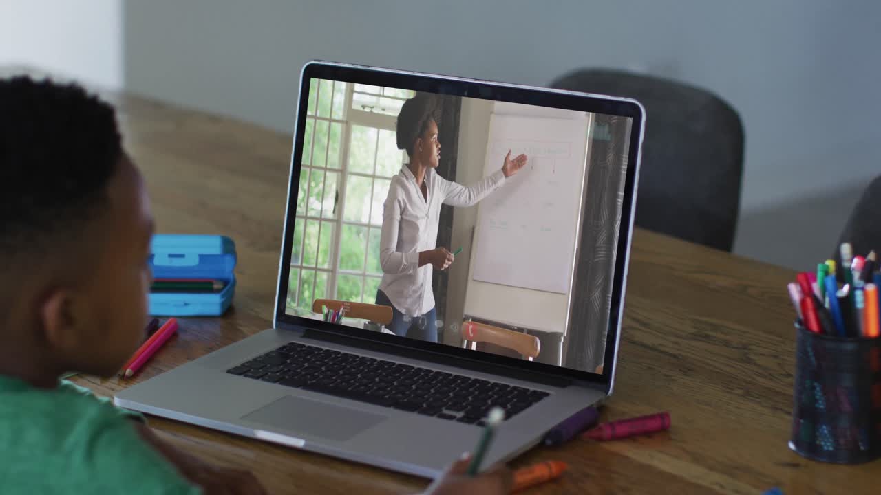 African american boy having a video call on laptop while doing homework at home