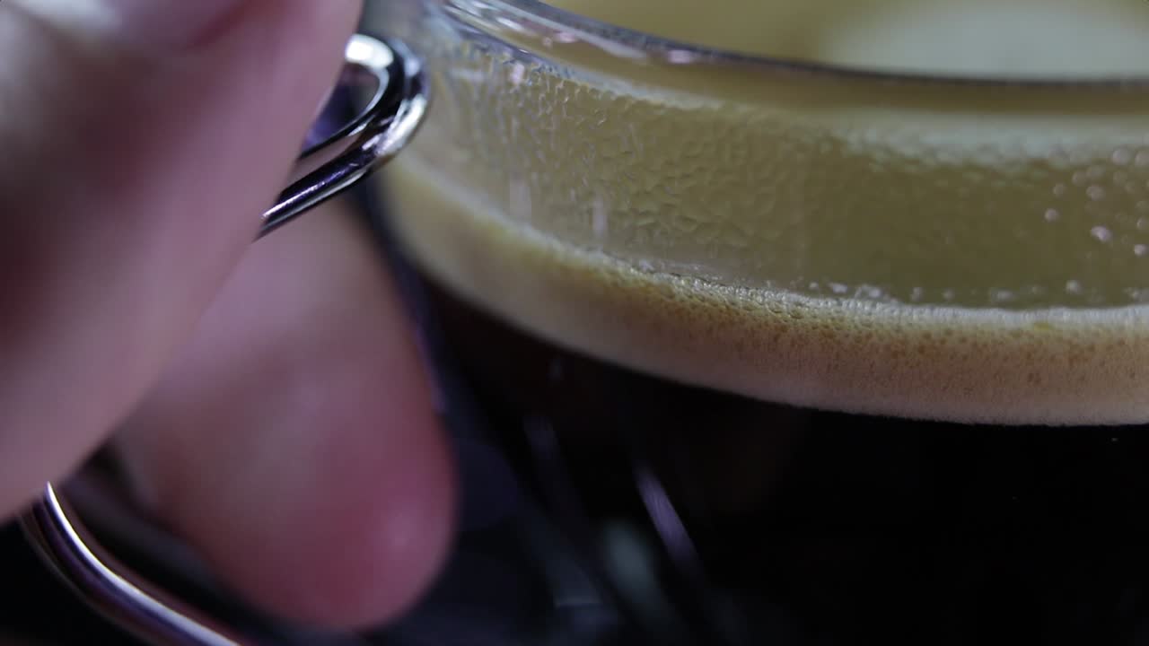 Closeup of hand taking a fresh cup of coffee from expresso machine - macro
