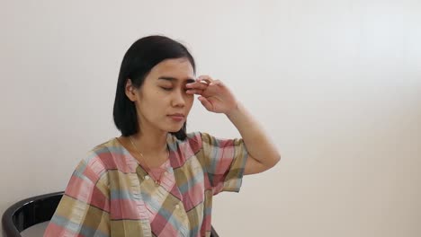 그녀의 눈을 비비는 동안 집에서 의자에 앉아 젊은 아시아 여자