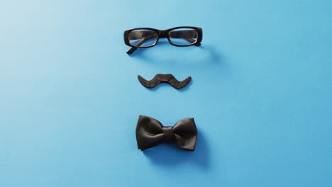 video de bigote falso, gafas negras y pajarita negra sobre fondo azul con espacio para copiar.