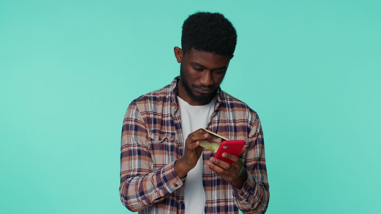 Young man using credit bank card and smartphone while transferring money, purchases online shopping
