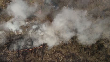 aerial top-down trucking shot over the wildfire in the suburban area covered by a thick smoke