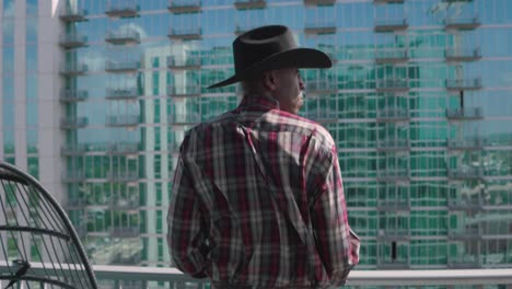 black man with black cowboy hat looking out from balcony