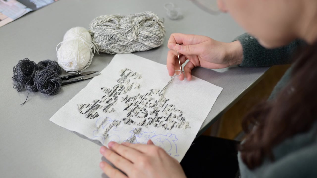 Close up of hands working with textile samples or fabric swatches on a design table, showing attention to detail in material selection and fabric composition