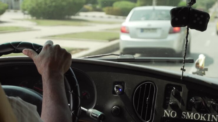 SLOW MOTION: Conducente con guida a destra in un'auto vecchia che tiene il volante.