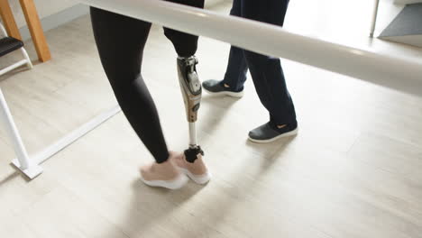 two people standing in prosthetic lab, one with a prosthetic leg, practicing walking