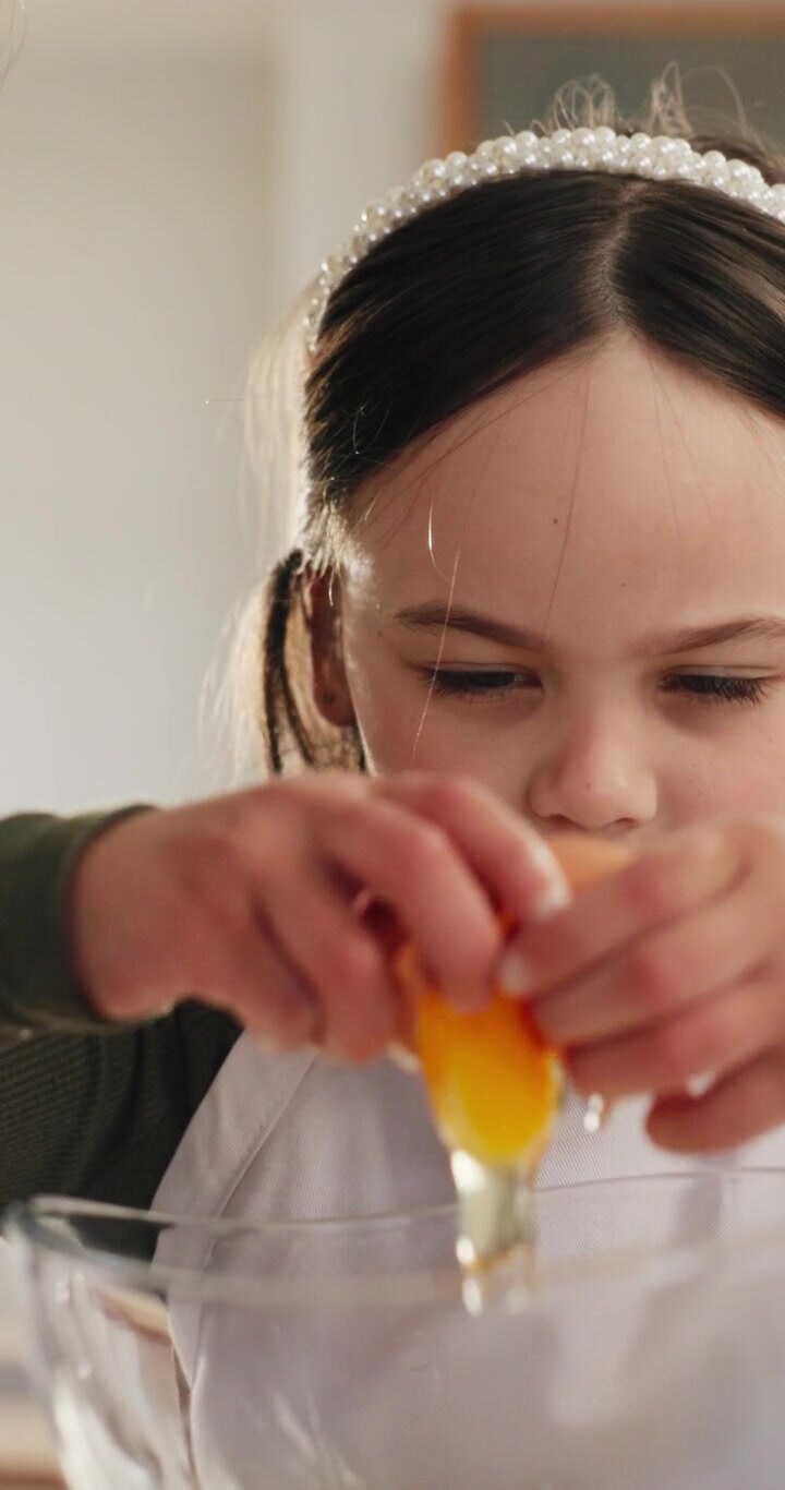 Young Girl Cracking an Egg into a Bowl with Her Mother