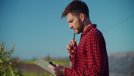 farmer in greenhouse calculating costs and profits
