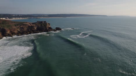 waves crashing against towering rock cliffs of the coastline of atlantic ocean at nazare