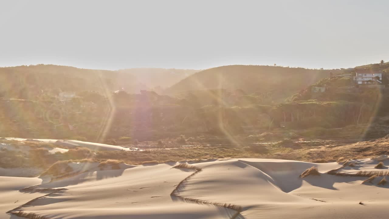 View of sand dunes and hills in Portugal with sun shining in background