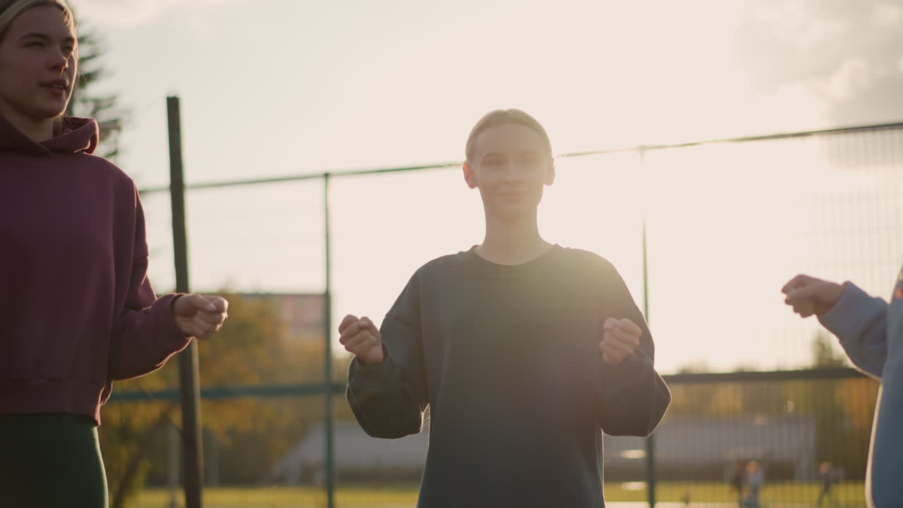 세 명의 젊은이들이 피트니스 활동을 하며, 빛이 그 주변에 빛나고, 바 울타리, 초록색, 그리고 배경에 보이는 축구장