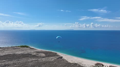 paragliding over a remote beach with stunning blue ocean - aerial