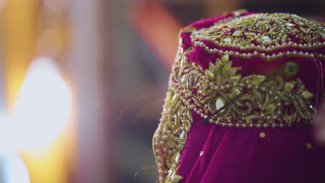 a stunning shot of a bride wearing a magenta-colored shawl with a typical golden beast embroidery on it