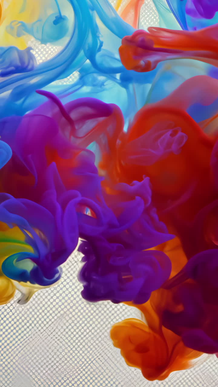 Colorful Swirls of Ink Blending in Water at a Creative Studio. Vibrant colors mix together in a fluid motion, creating a mesmerizing display of swirling patterns in water. Vertical video