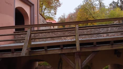 a drone begins to rise slowly along a bridge under the bridge you can see two tunnels over the bridge there is a road leading to the city gate and cars enter and exit it