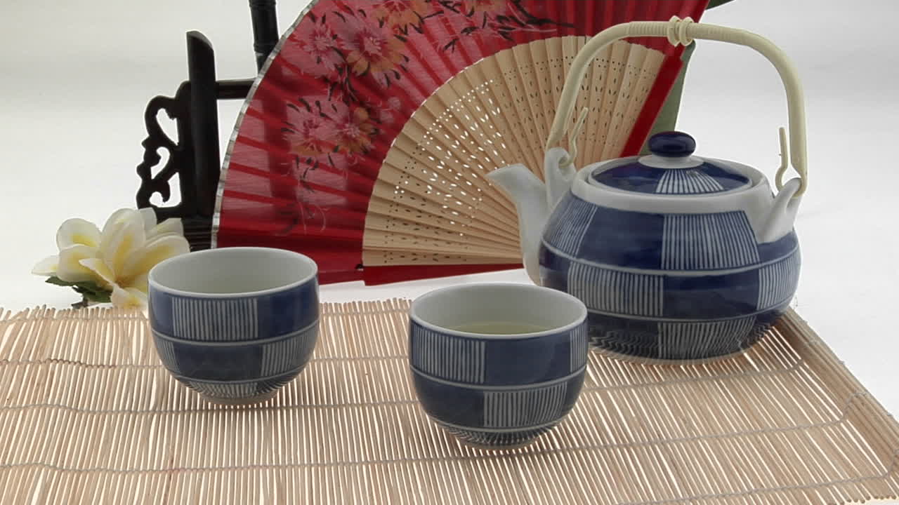일본 차 세트는 일본식 팬과 꽃으로 둘러싸여 있습니다.