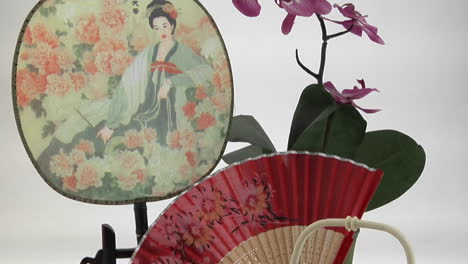 a japanese tea set is framed by a japanesestyle fan and flowers