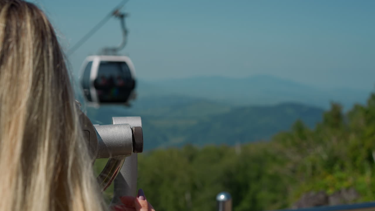 Female tourist adjusts tower viewer at cable way station