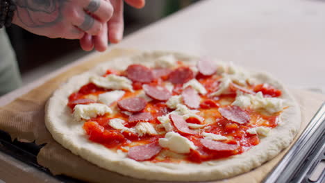 adding pepperoni to pizza dough