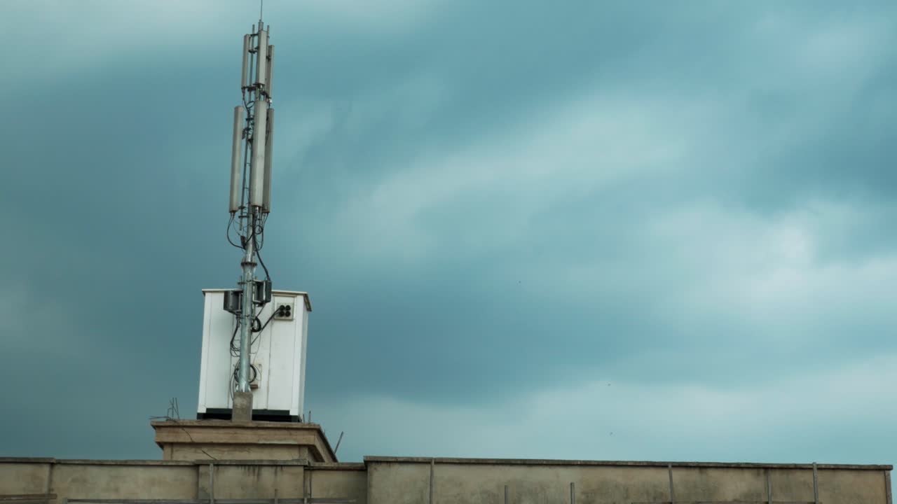 Antenna per telefonia mobile e stazione base situate su un tetto di città contro un cielo grigio e coperto a Yaoundé, Camerun. Vista dal basso