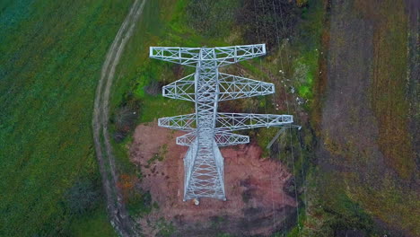 aerial drone tilt down shot over a newly constructed electric pole for placing electric lines through green grasslands at daytime