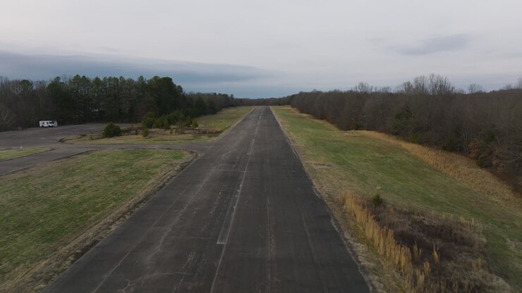 Volo basso di drone lungo il centro di una piccola pista in un aeroporto dismesso e deserto nell'Arkansas rurale.