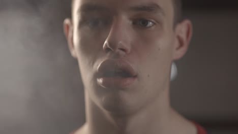 closeup of a young man vaping with white smoky air coming from his mouth - slow motion