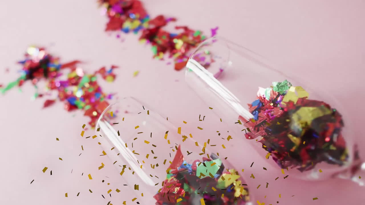 Animation of confetti over glasses with confetti on pink background
