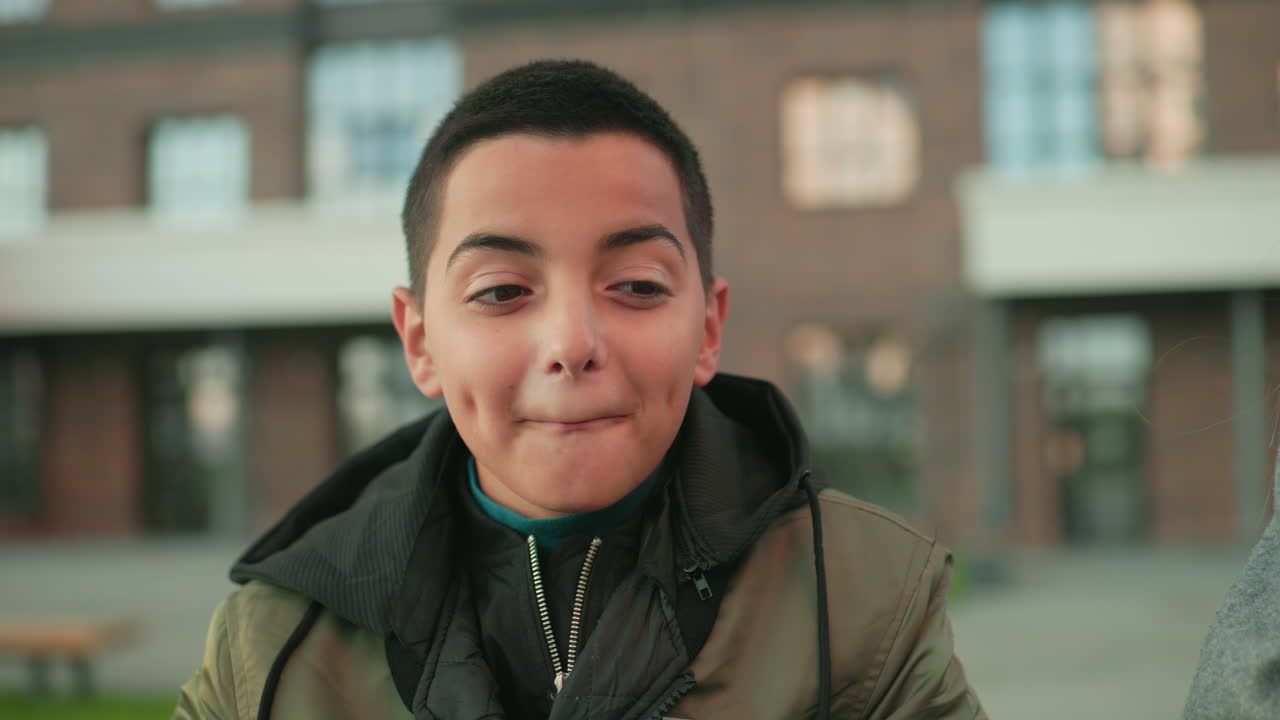 Boy laughs in surprise as aunt makes mistake during playful moment, both smiling warmly outdoors near building background, capturing joy, family bonding, and candid reaction of shared happiness