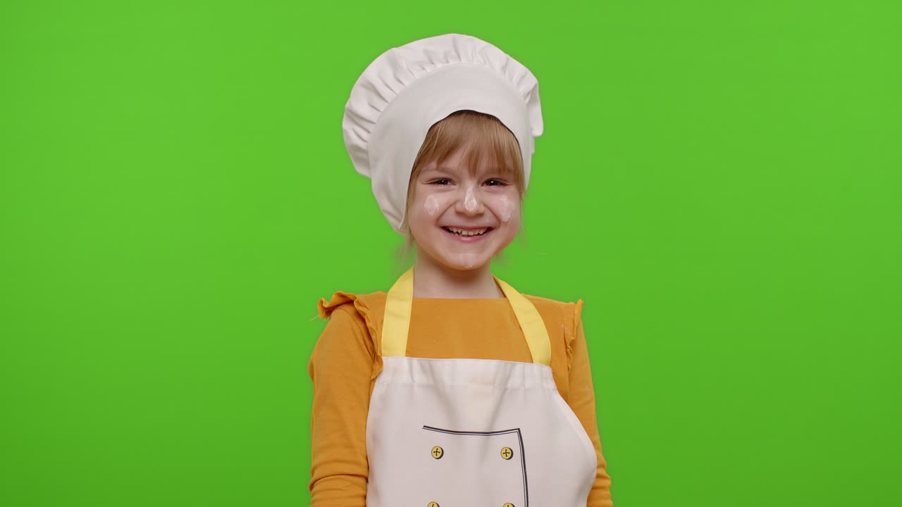 Affascinante bambina vestita da cuoca chef che ride a crepapelle dopo aver sentito un aneddoto ridicolo