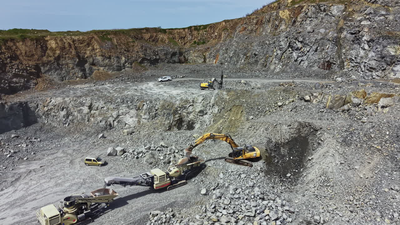 Granite quarry site with machinery working on stone extraction and site preparation in a rural area during daylight