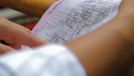 engineer pointing his finger on whiteprint plan at construction site