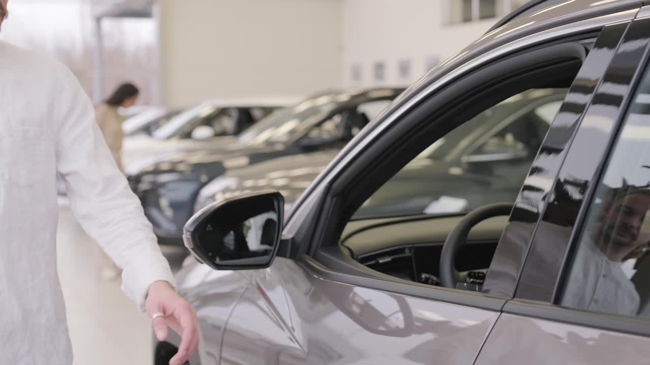 una hermosa pareja de jóvenes en la sala de exposición de automóviles eligiendo un coche nuevo para comprar.
