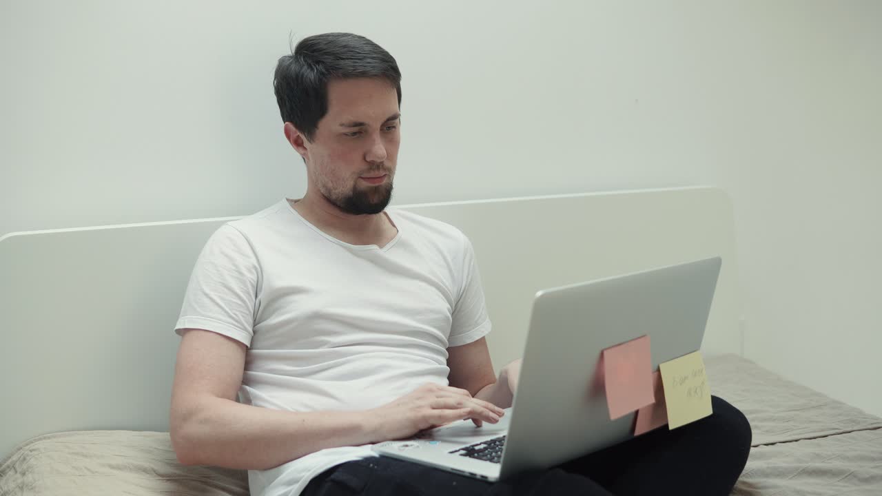 침대에 노트북으로 일하는 남자