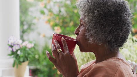 close up of senior african american woman drinking coffee while sitting on the porch of the house