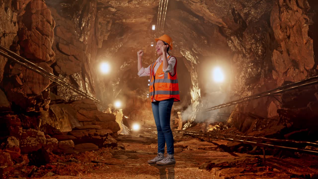 Full Body Side View Of Asian Female Engineer With Safety Helmet Screaming Goal Celebrating Working In Underground Mine Tunnel