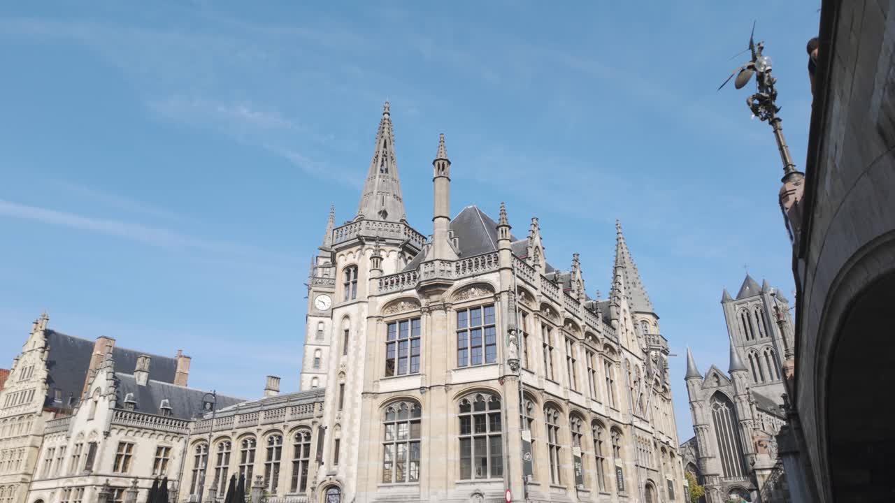A picturesque view of Ghent's historic buildings near Saint Michael's Bridge, showcasing stunning medieval architecture against a clear blue sky.