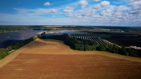 aerial view of large solar array farm surrounding wheat field