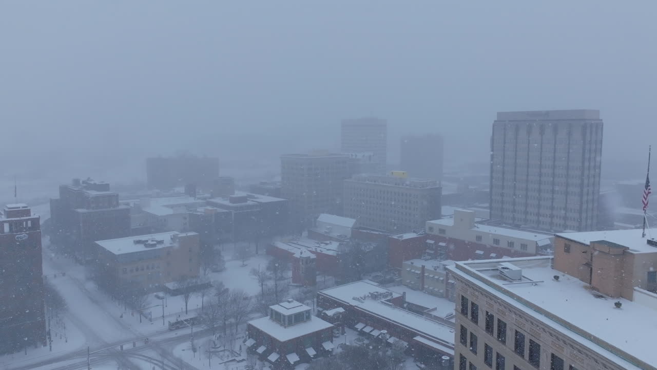 Slow aerial footage moving through the downtown buildings of Chattanooga, TN during a snowstorm.