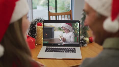 Caucasian-granddaughter-and-grandfather-on-video-call-with-grandson-at-christmas-time