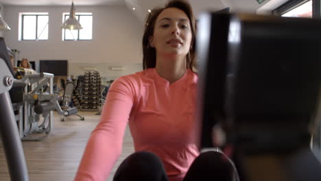 Woman-on-rowing-machine-at-a-gym,-selective-focus