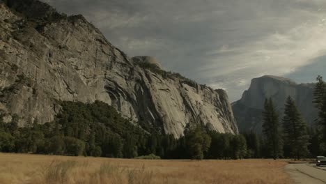 slow pan right across grassland with view of granite cliffs at yosemite