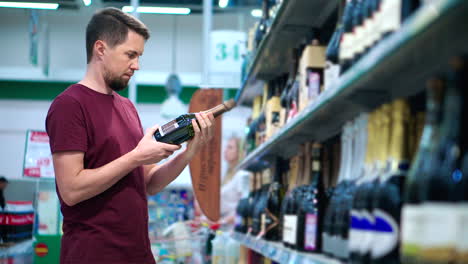 hombre mirando una botella de champán en la tienda de comestibles