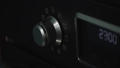 primer plano estático de la mano ajustando el dial del equipo electrónico, cuarto oscuro